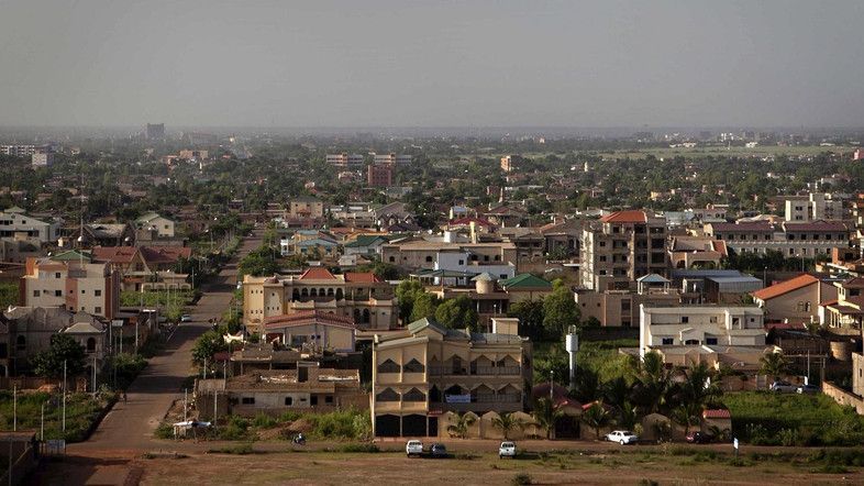 Cityscape of buildings and trees under a hazy sky, likely an African city.