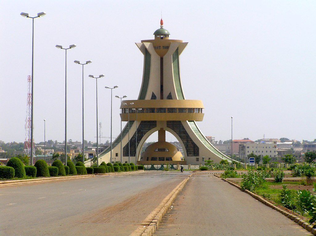 A tall, modern monument in Ouagadougou, Burkina Faso, with a large circular platform, flanked by converging pillars and a central tower.