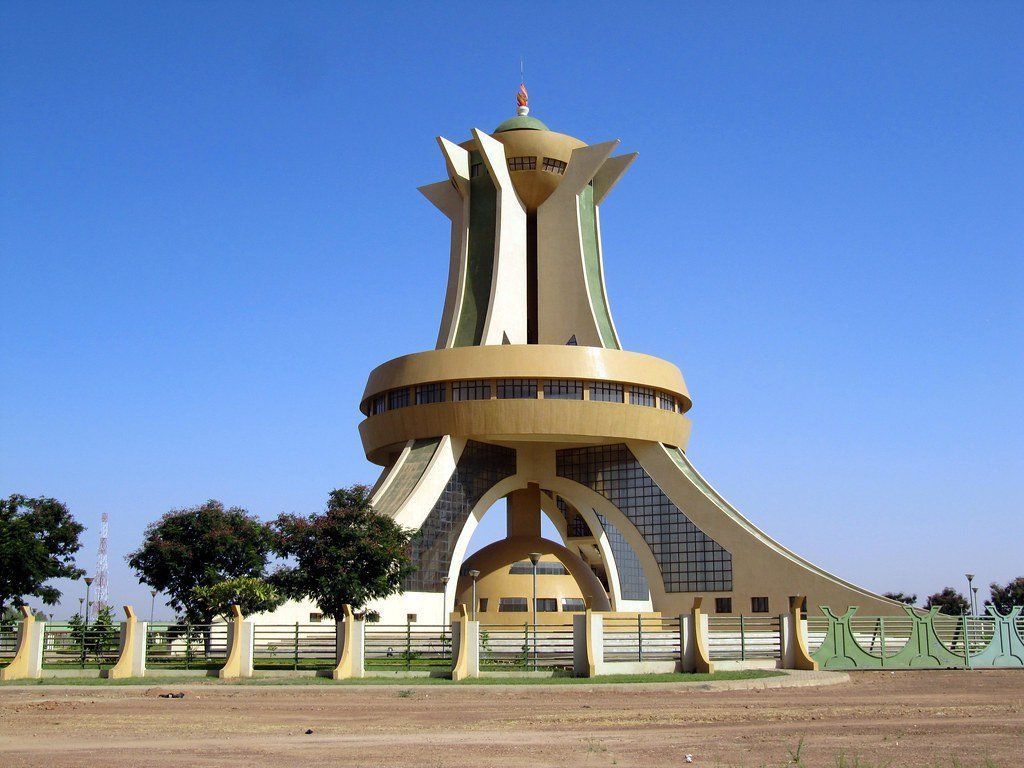 Monument des Martyrs in Ouagadougou, Burkina Faso, a beige and white architectural structure with a distinctive geometric design against a clear blue sky.