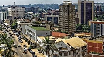 Cityscape of Yaoundé, Cameroon, with tall buildings, busy roads, and lush vegetation.
