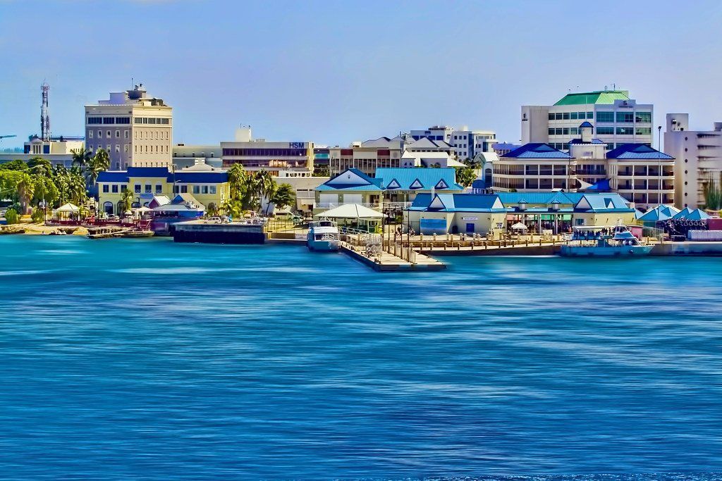 Waterfront view of a city with white and blue buildings, blue water, and a clear sky.