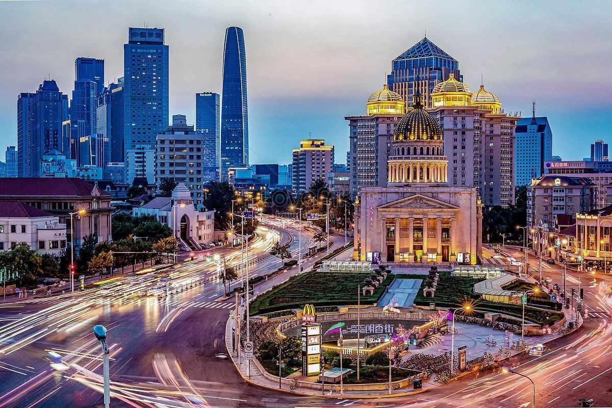 Cityscape at dusk with illuminated buildings and traffic trails. A large ornate building is in the foreground.
