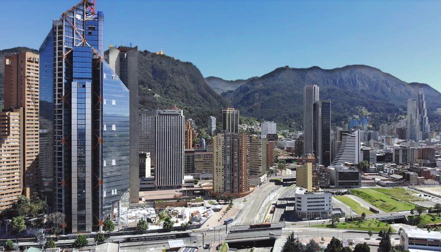 City skyline with modern skyscrapers under a clear blue sky, mountains in the background.