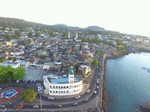 Aerial view of Moroni, Comoros, with a white mosque, harbor, and city buildings.