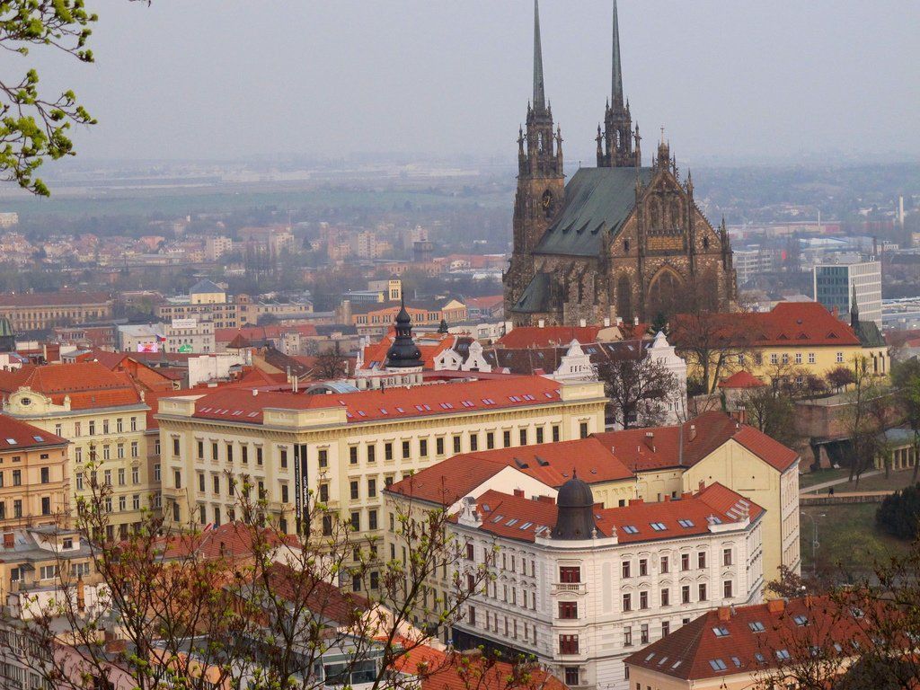 Cityscape of Brno, Czech Republic, with the Cathedral of St. Peter and Paul dominating the skyline behind red-roofed buildings.