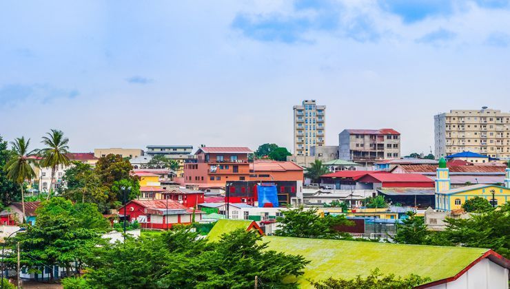 A cityscape with colorful buildings, including apartments, and trees under a cloudy sky.