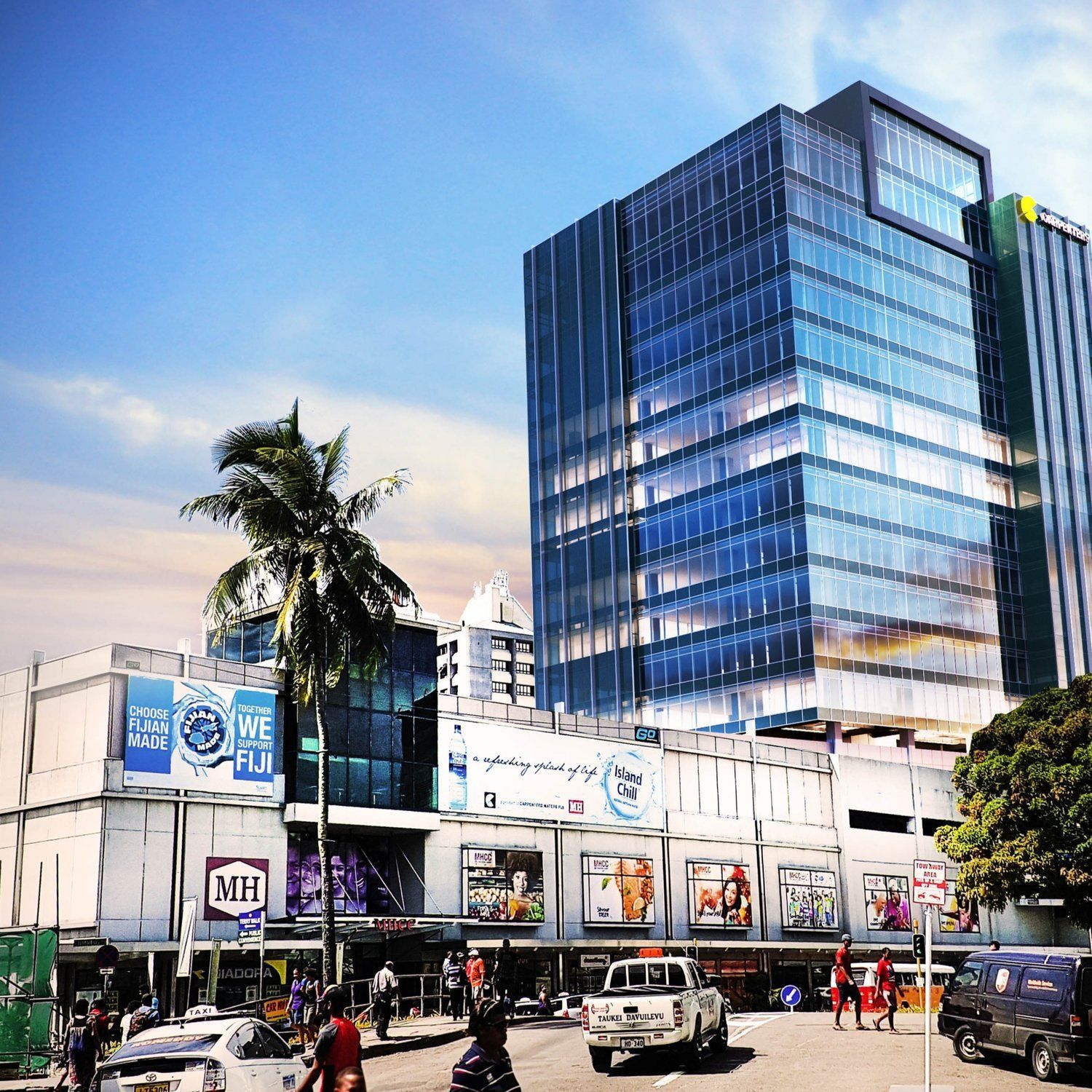 A modern building and shopping center with advertisements and people in a city setting under a blue sky.