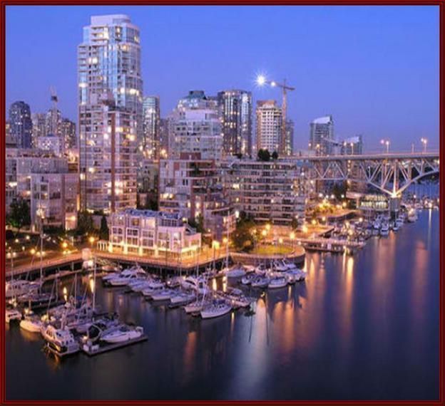 Night view of Vancouver skyline with lit skyscrapers, a bridge, and boats docked in the harbor reflecting lights on the water.