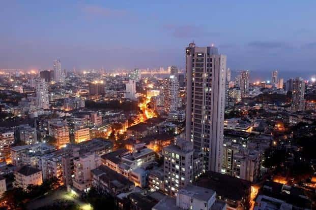 Nighttime cityscape of Mumbai, India, featuring illuminated high-rise buildings and a busy street.