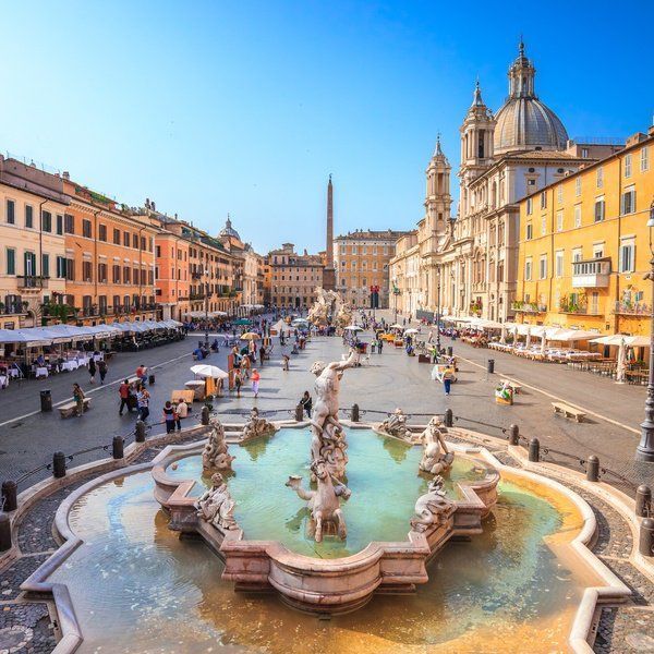 Piazza Navona in Rome, Italy. The baroque fountain in the foreground with people milling about, and buildings in the background.
