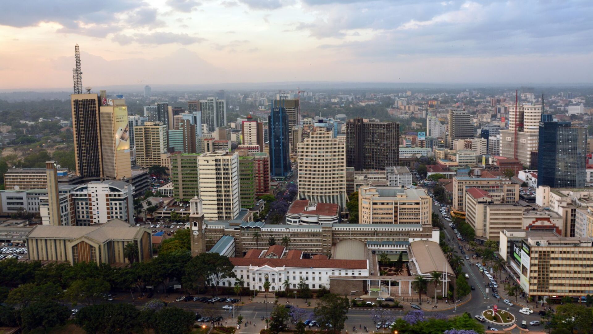 Aerial view of Nairobi, Kenya, with a skyline of modern buildings under a cloudy sky.