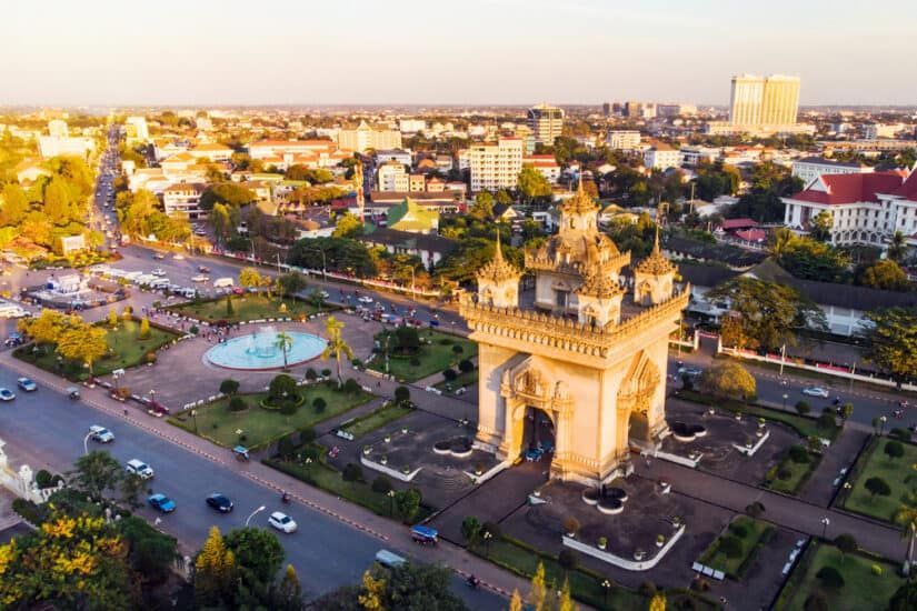 Patuxai Victory Gate in Vientiane, Laos, bathed in golden sunlight. A landmark in the city surrounded by a park and roadways.