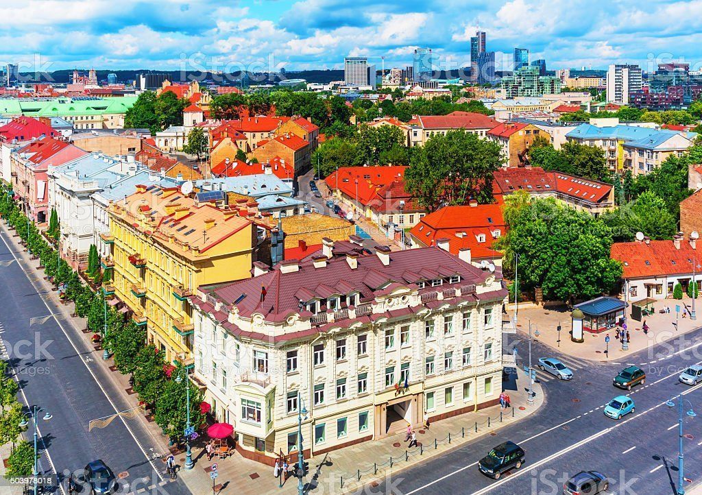 Aerial view of Vilnius, Lithuania. Historic buildings with red tile roofs, trees, and a cityscape backdrop.
