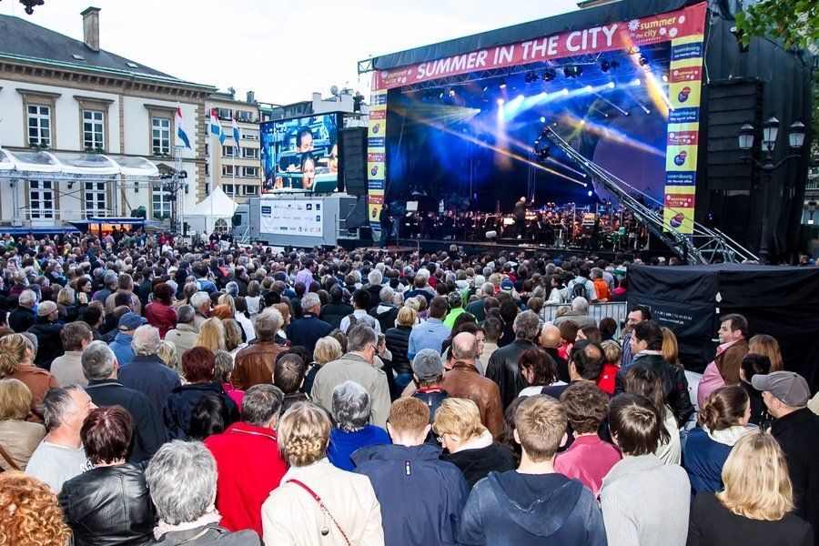 Large crowd watches a concert on an outdoor stage. 