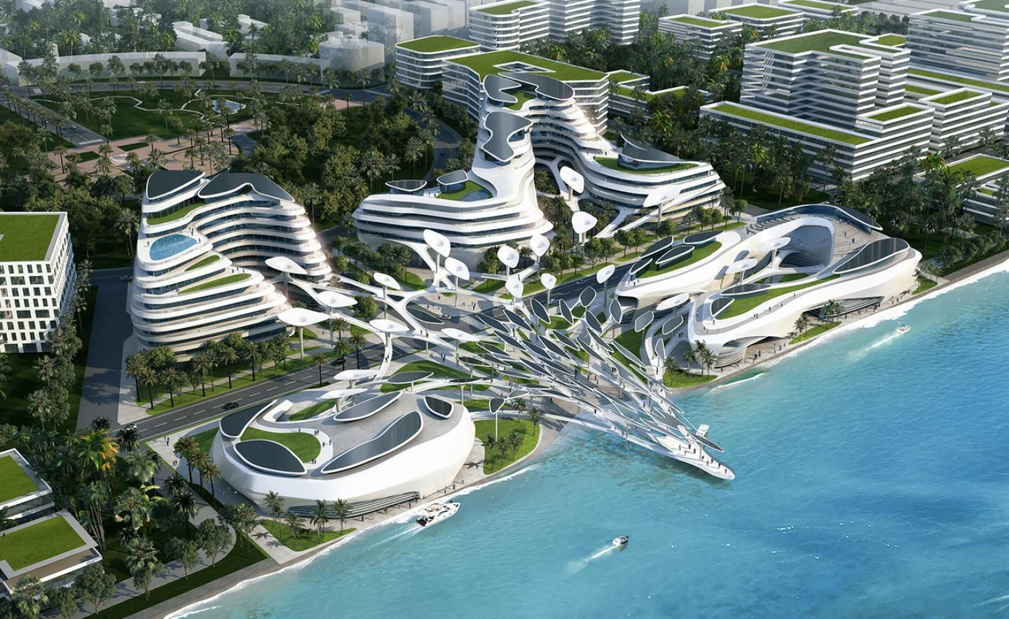 Aerial view of a futuristic coastal city with white, organic-shaped buildings featuring green rooftops and a connecting network, next to blue ocean waters.