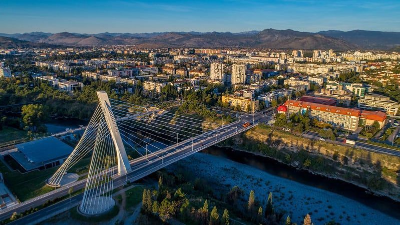 Cable-stayed bridge over a river in a city with buildings and mountains in the distance.