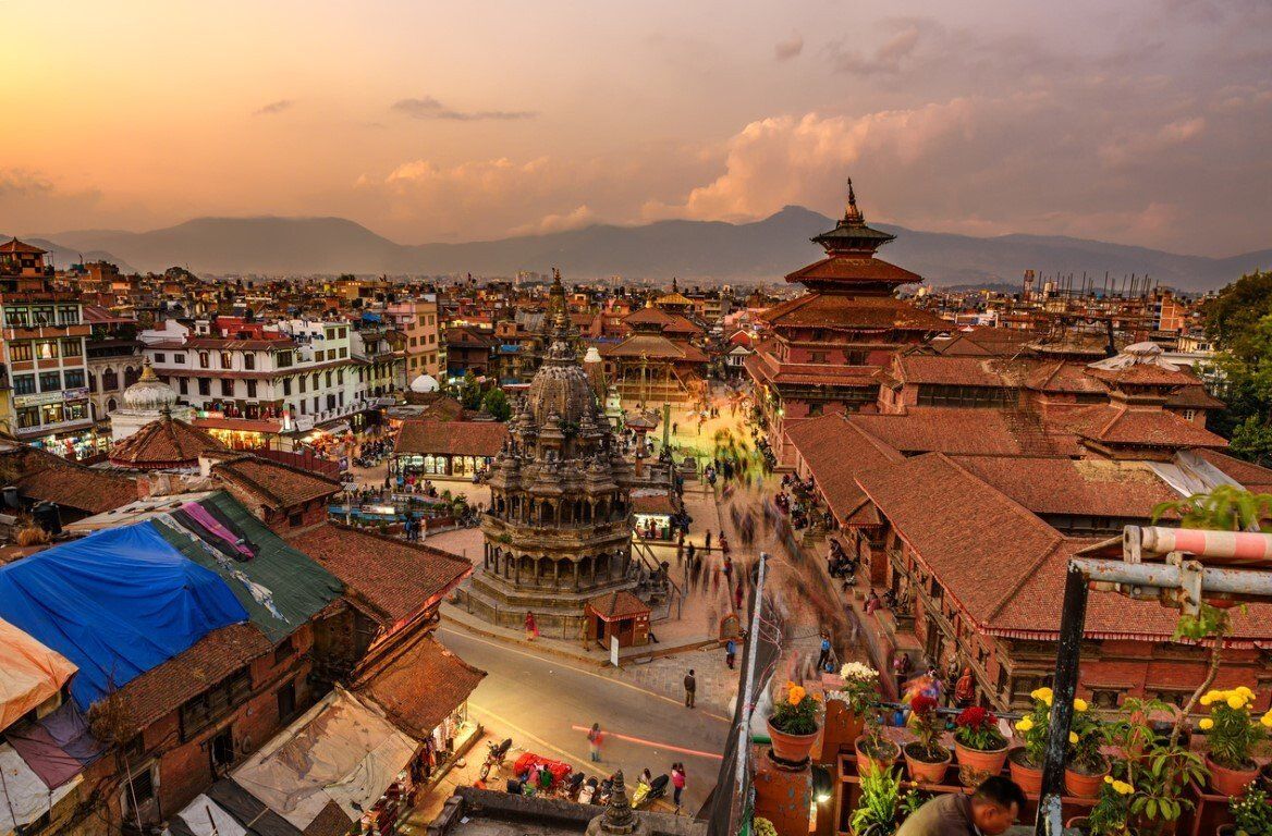 Overhead view of Bhaktapur Durbar Square, Nepal, at sunset.  Red-tiled rooftops and ornate temples are bathed in warm light.