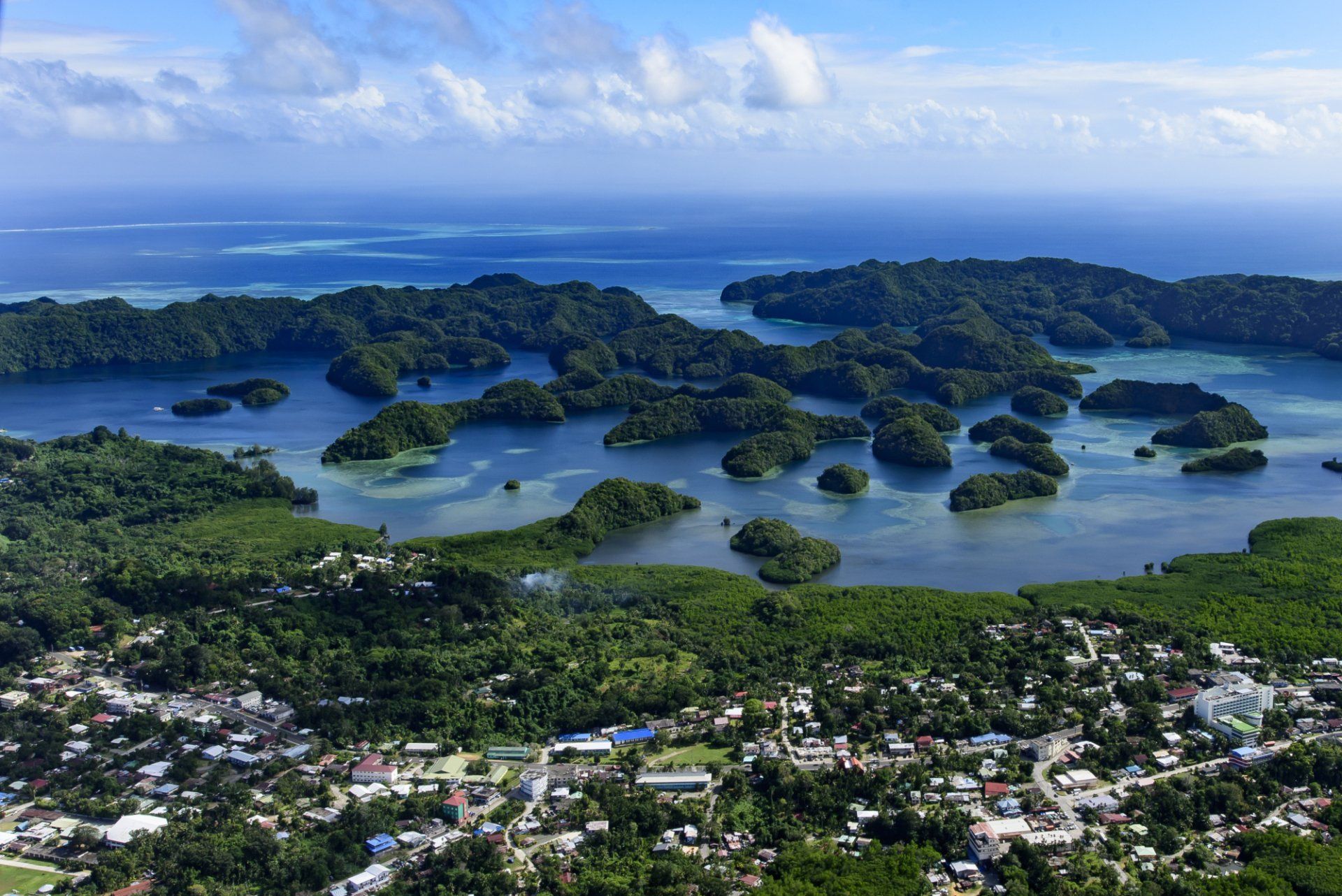 Aerial view of a tropical island chain with lush green islands, blue water, and a coastal town.