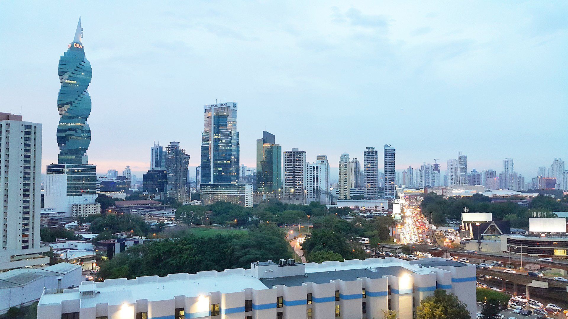 Skyline of Panama City, Panama at dusk, featuring modern skyscrapers and a prominent, twisting tower.