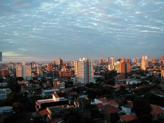 City skyline at sunrise or sunset with buildings and a cloudy sky.