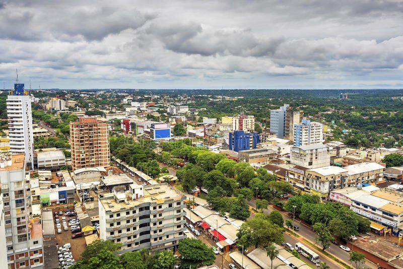 Aerial view of Cuiabá, Brazil, showing a city skyline with buildings, parks, and a cloudy sky.