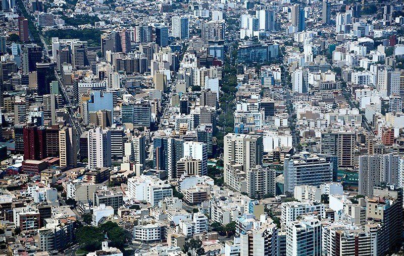 Aerial view of a densely packed city with tall buildings, various colors, and long, straight streets.