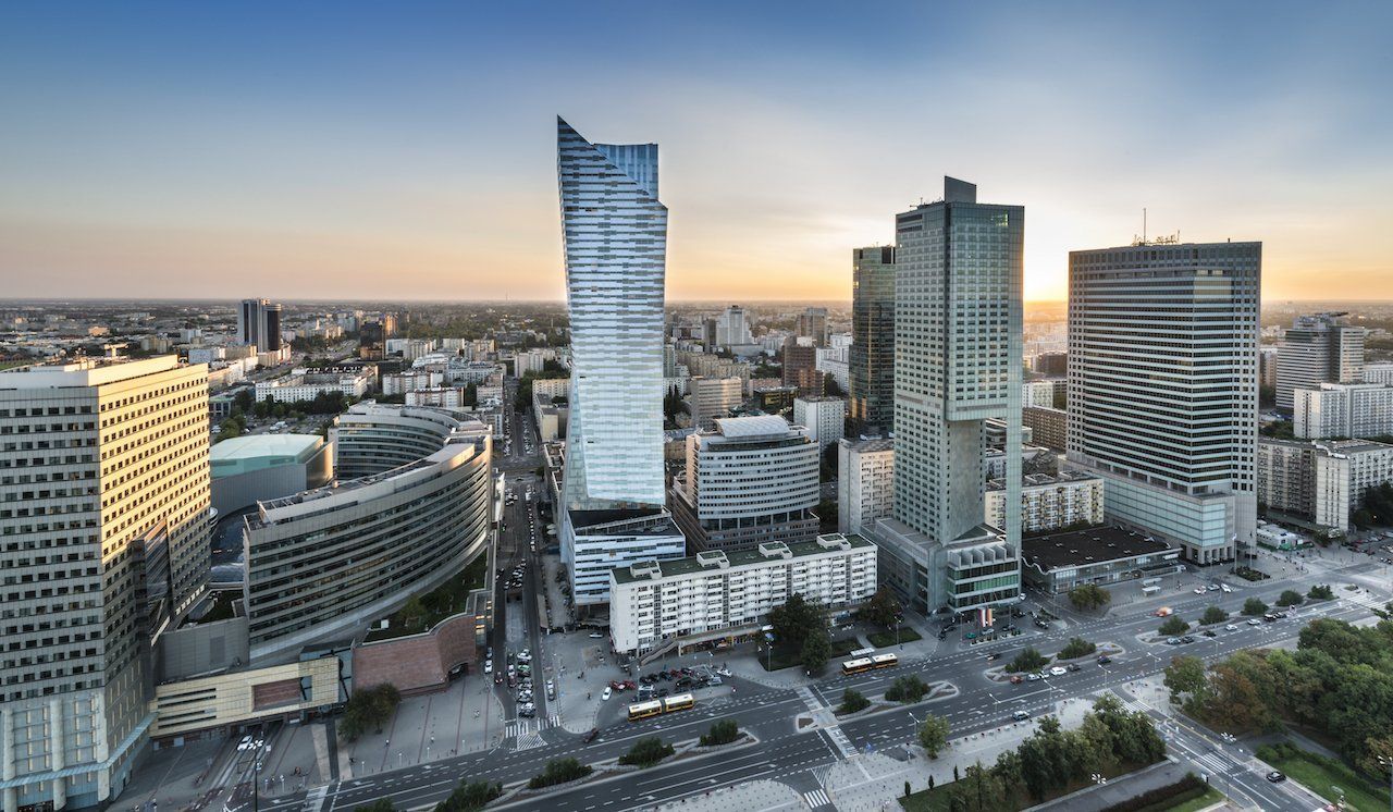 Aerial view of Warsaw, Poland, featuring modern skyscrapers and city buildings at sunset.