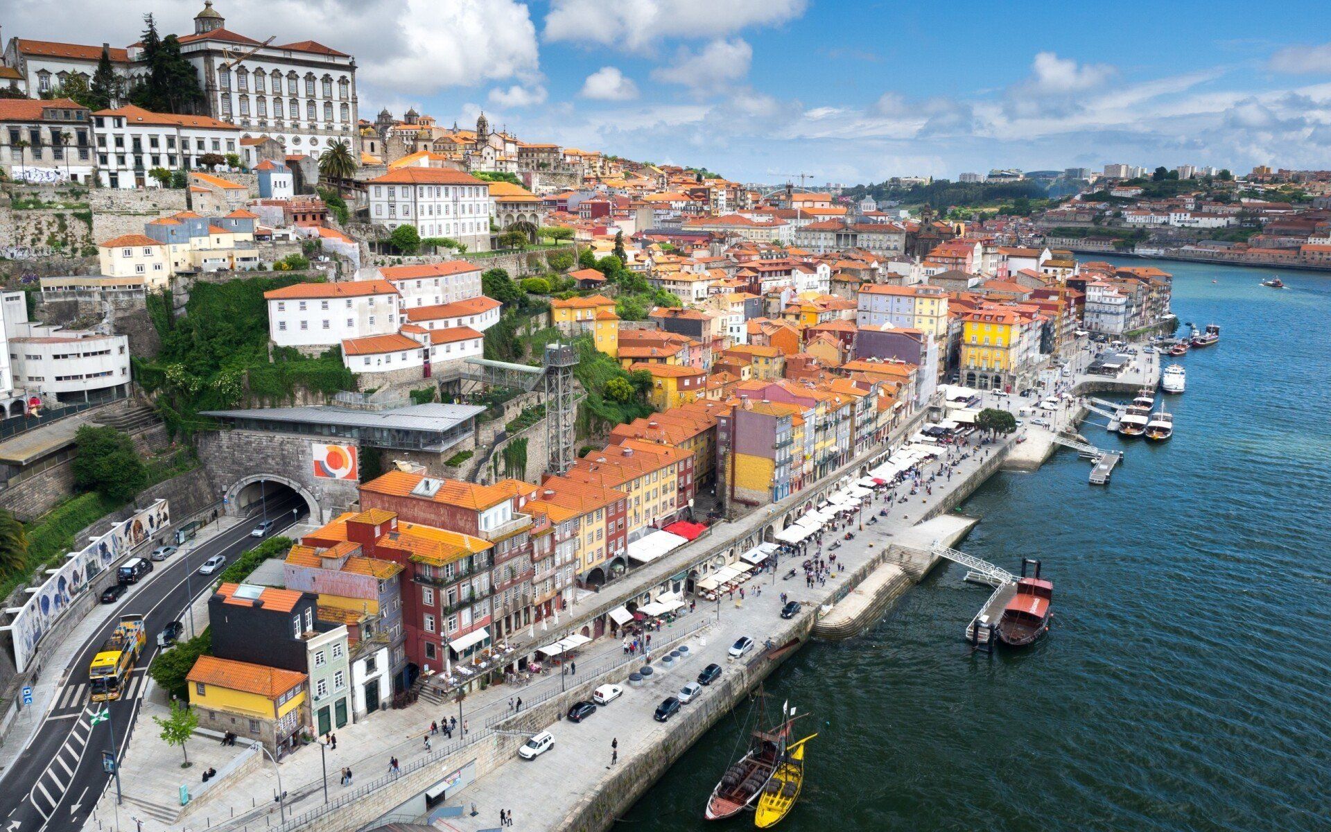 View of Porto, Portugal, with colorful buildings along a waterfront, the Douro River, and a bright blue sky.
