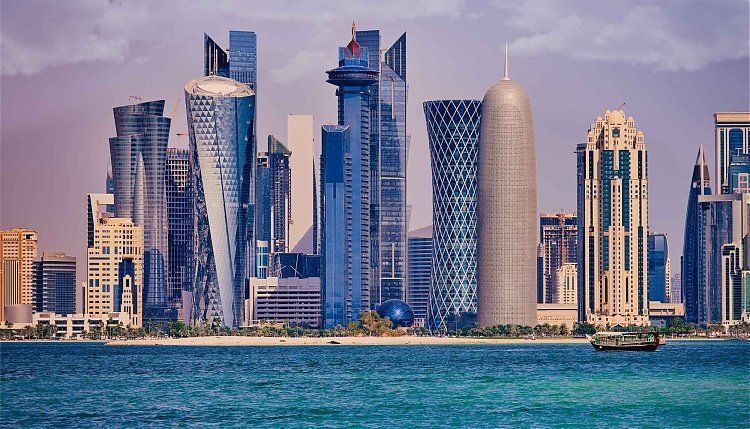 Doha, Qatar skyline with modern skyscrapers against a cloudy sky, view from the water.