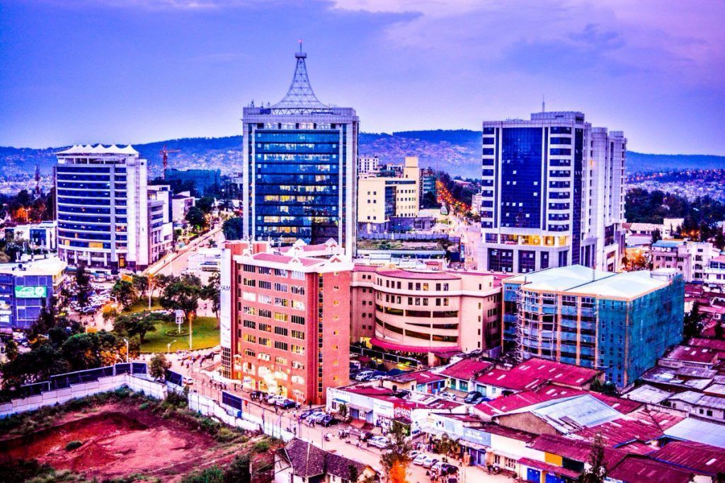 Skyline of Kigali, Rwanda, featuring modern high-rise buildings, a vibrant cityscape under a blue and purple sky.