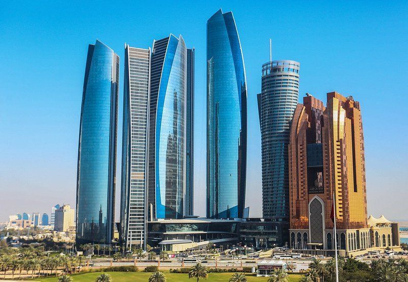 Modern skyscrapers in Abu Dhabi, United Arab Emirates, with blue and gold glass facades.