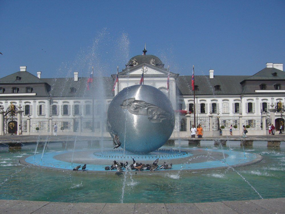 A fountain with a large silver globe sculpture in front of the Presidential Palace in Bratislava, Slovakia.
