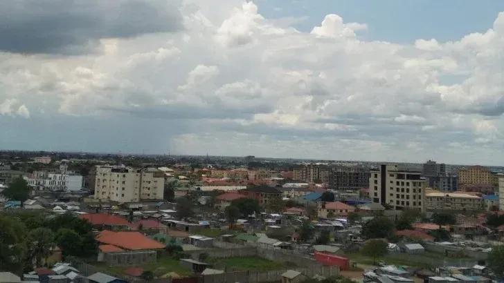 A cityscape under a cloudy sky. Several buildings are visible, suggesting an urban setting.