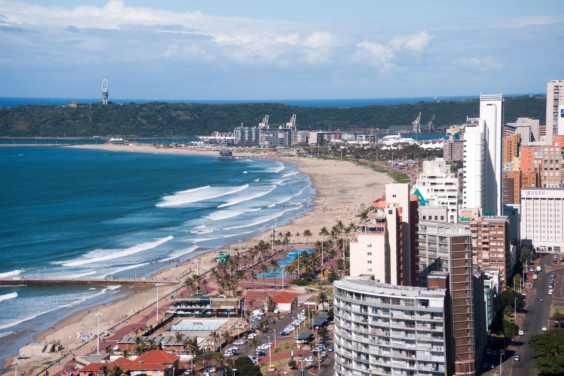 Coastal cityscape with sandy beach, ocean waves, and high-rise buildings under a blue sky in Durban, South Africa.