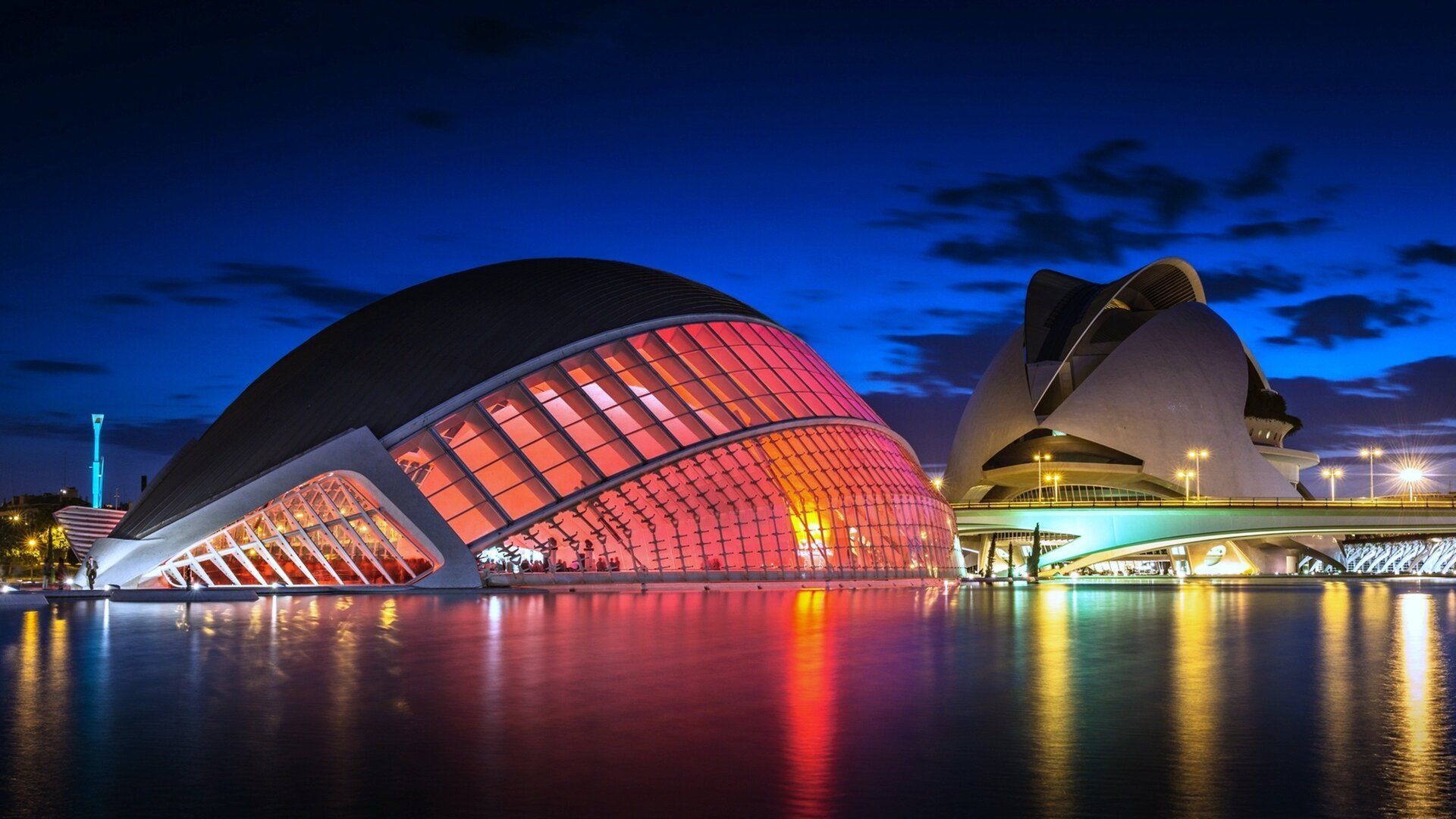 Night view of the City of Arts and Sciences in Valencia, Spain, with illuminated modern buildings reflecting in the water.