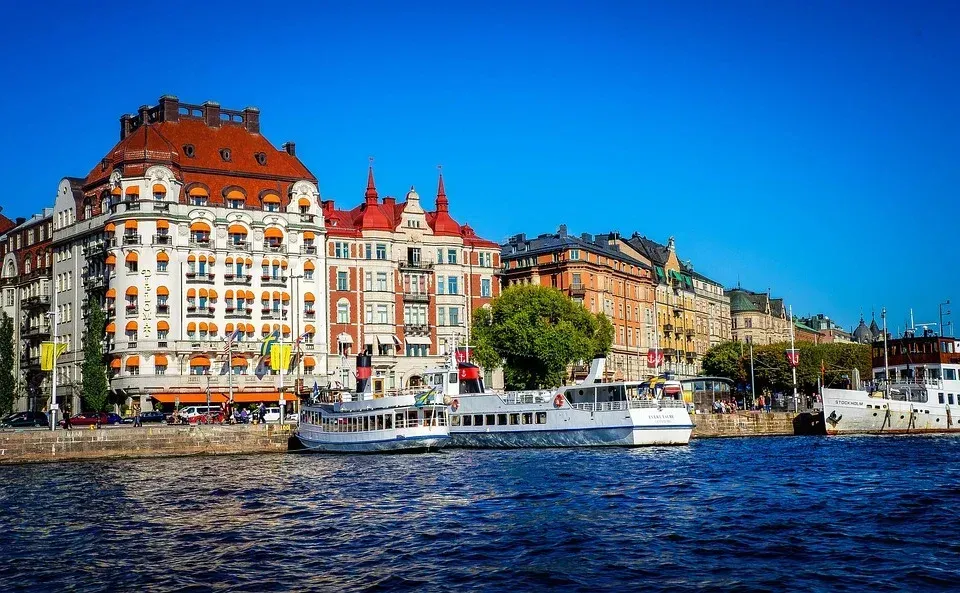 Waterfront buildings in Stockholm, Sweden, with boats in front on a sunny day, and a clear blue sky.