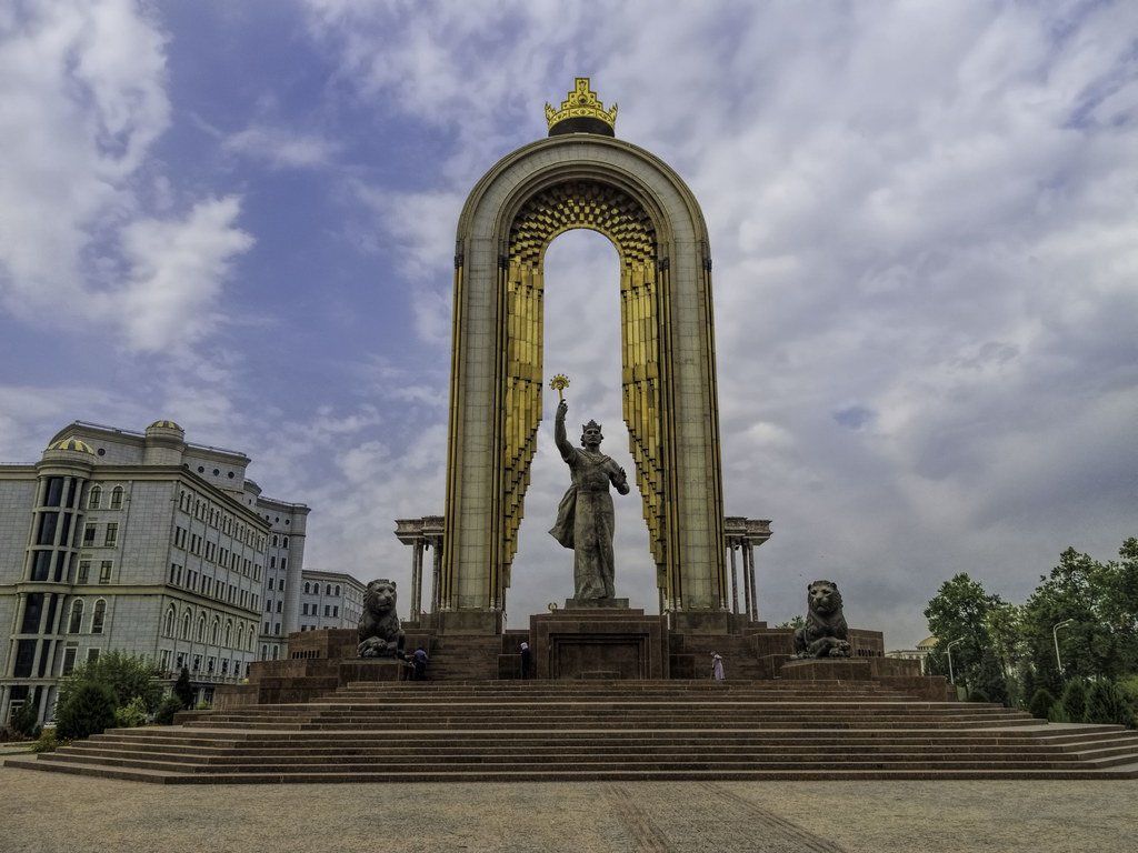 Monument in Tashkent, Uzbekistan, featuring a statue of a woman holding a scepter within a large golden arch.