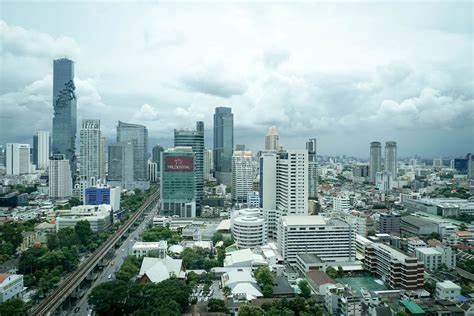 City skyline under cloudy sky, featuring skyscrapers and a railway line.