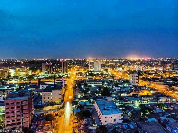 Nighttime cityscape with glowing streetlights and buildings under a dark blue sky.
