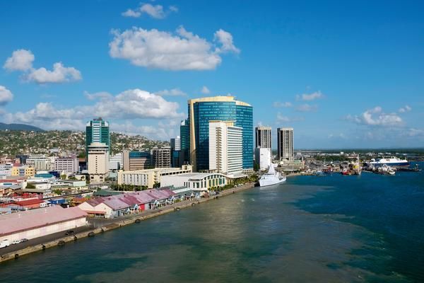 Skyline of Port of Spain, Trinidad, with a blue sky, skyscrapers, and a harbor with ships.