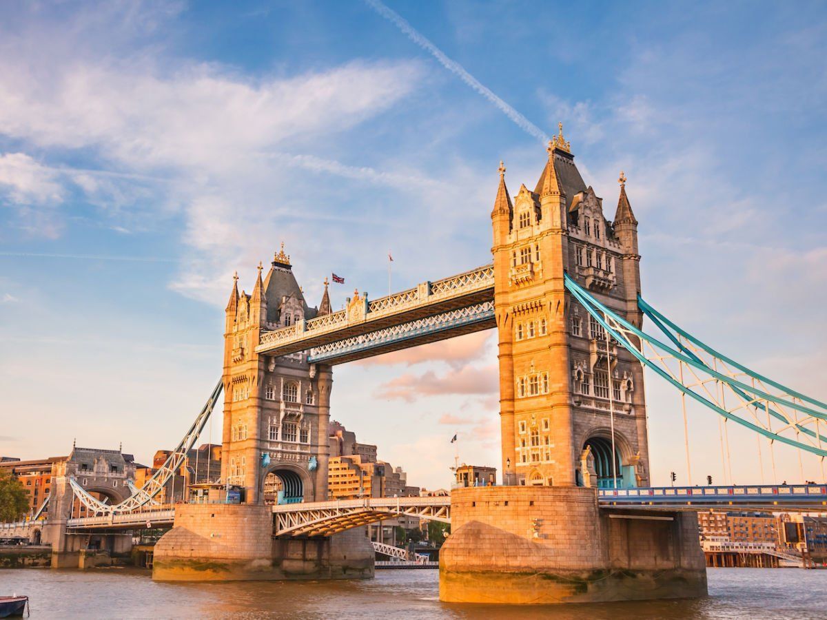 Tower Bridge in London, bathed in golden sunlight against a blue sky.