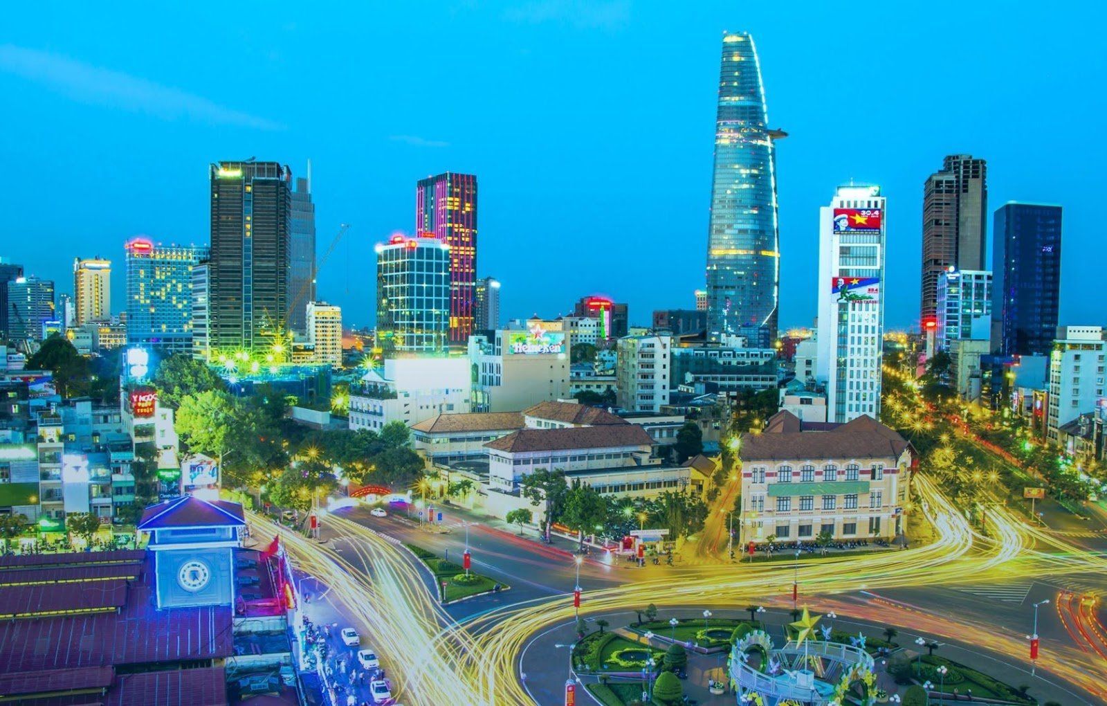 City skyline at dusk in Ho Chi Minh City, Vietnam, with tall buildings and light trails from traffic.