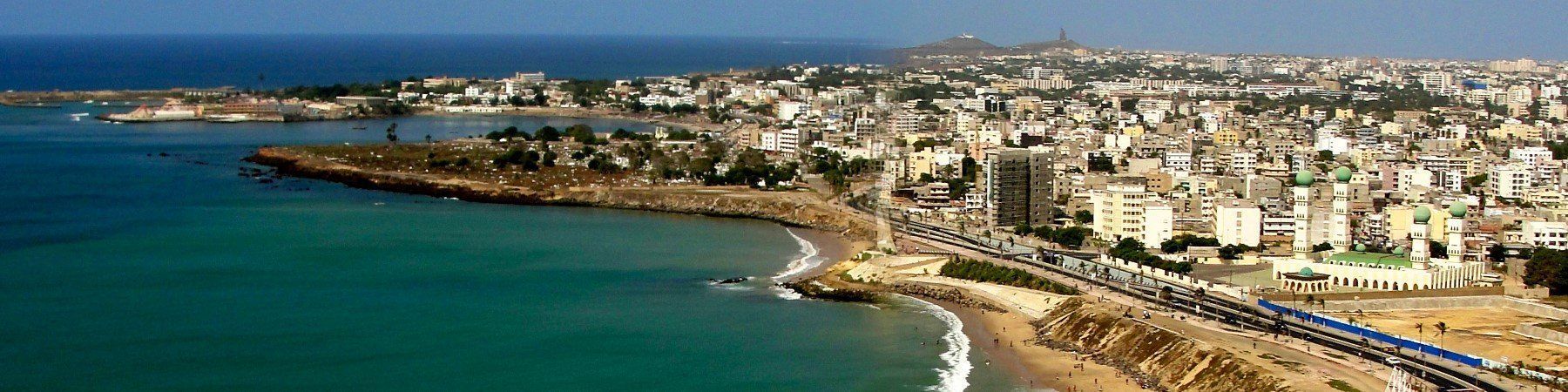 Coastal city with buildings and a beach along the blue sea.