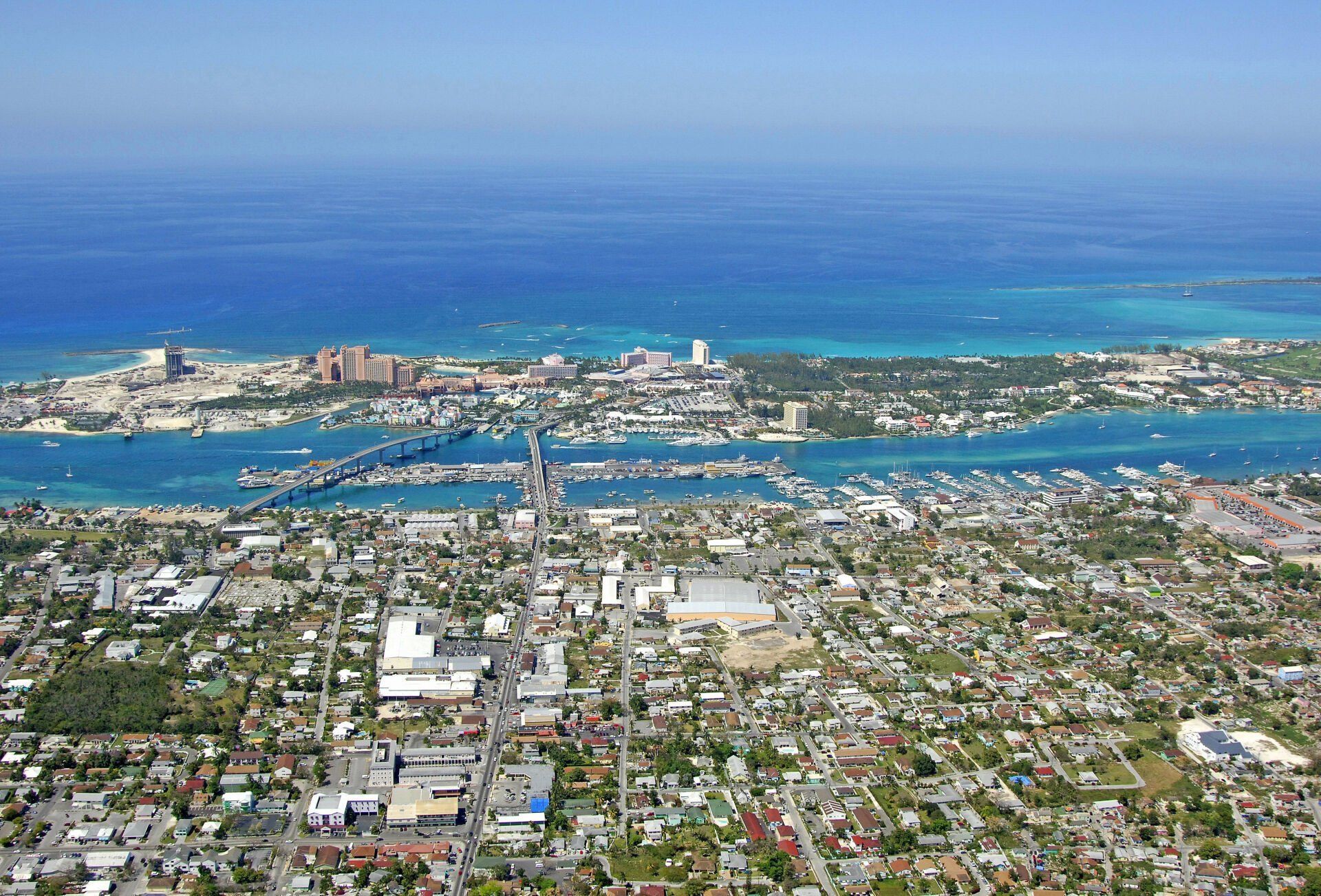 Aerial view of Nassau, Bahamas, showcasing a coastal city with turquoise water, buildings, boats, and a bridge.