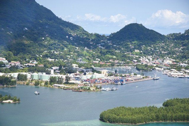 Coastal view of Mahe, Seychelles, with green mountains, blue harbor, and cargo docks.