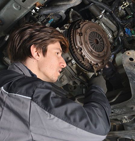 Auto mechanic working under the car and changing clutch