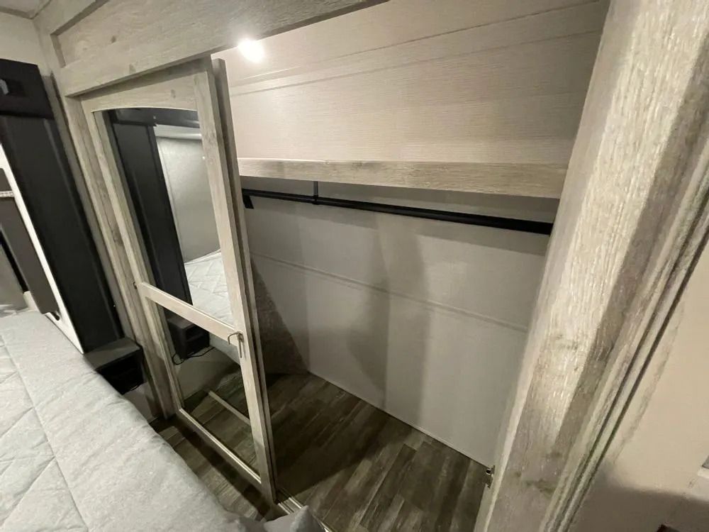 Closet interior with clothes rod and shelf, inside a bedroom with a bed