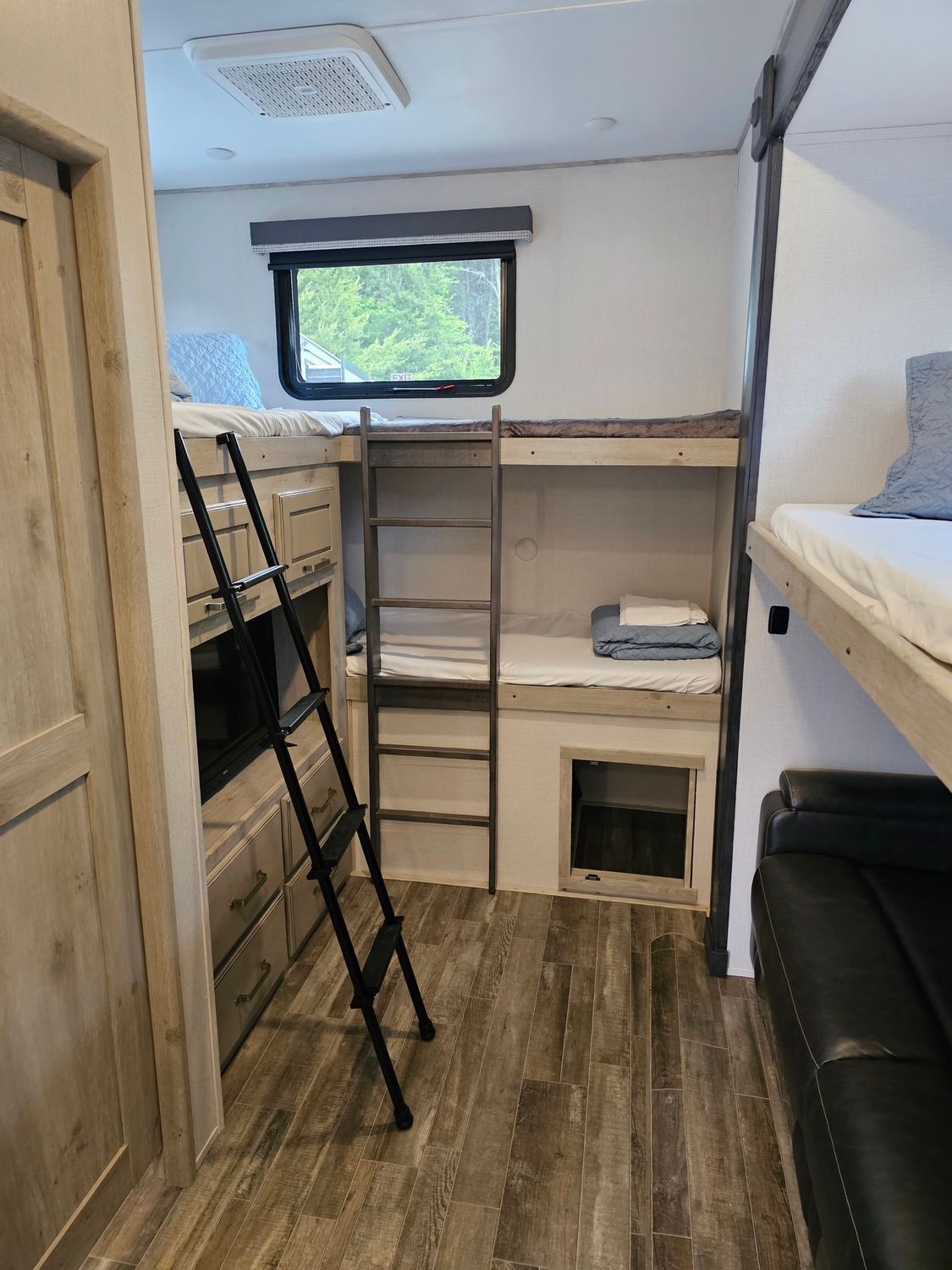 RV bunk beds with a ladder and window, white and gray interior.