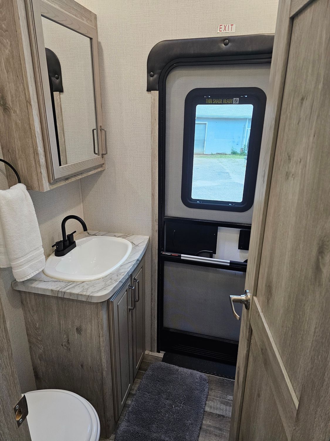 Bathroom interior with sink, toilet, cabinet, mirror, and door