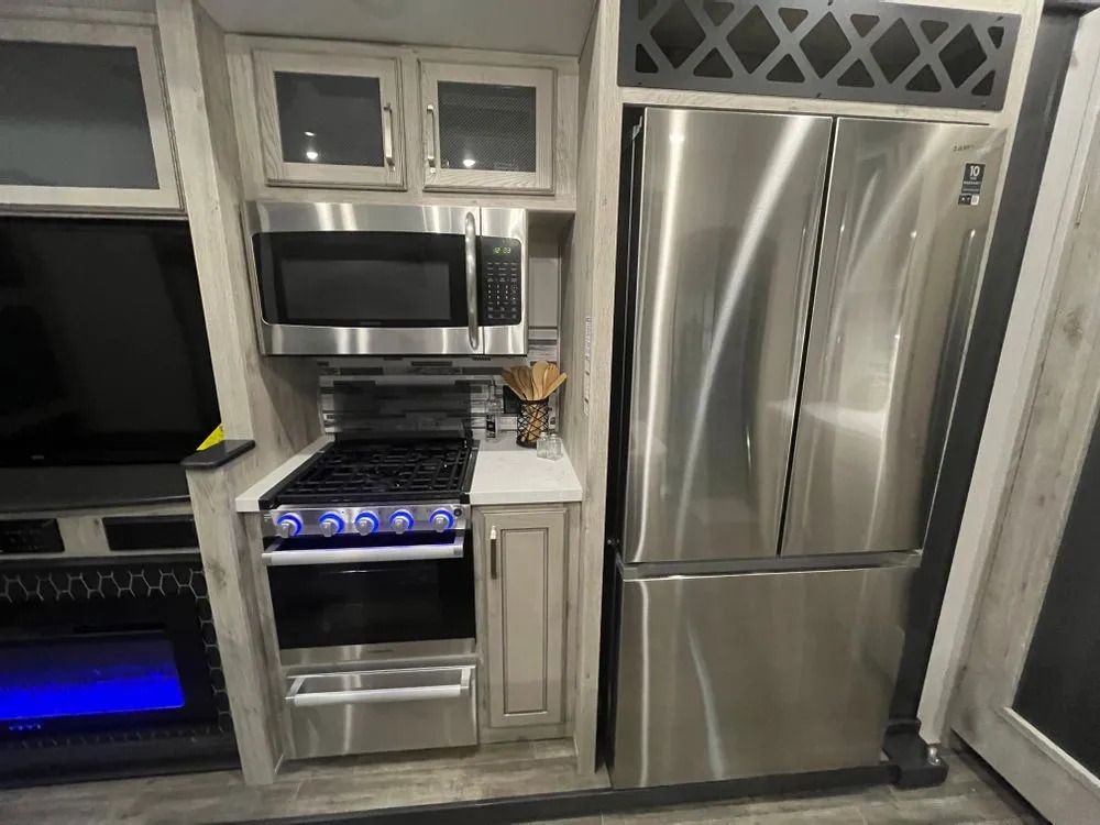 RV kitchen: Stainless steel appliances, including a refrigerator, microwave, and gas range.